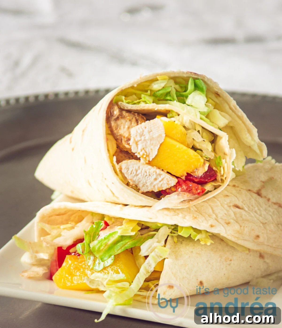 6 Irresistible Picnic Dishes for Your Ultimate Outdoor Gathering 7 Two vibrant and generously filled wraps with spicy chicken, crisp lettuce, sweet mango chunks, and diced tomatoes, elegantly arranged on a silver plate.