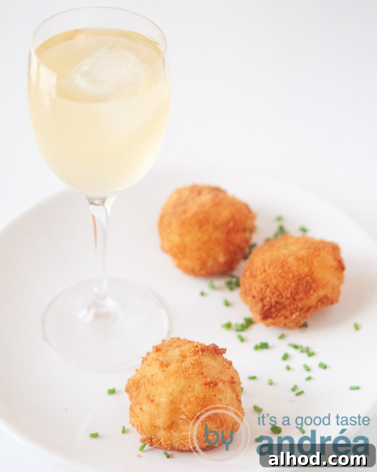 3 Dutch Bitterballen Recipes 5 Three shrimp bitterballen on a white plate, sprinkled with chives. A glass of white wine to accompany the dish