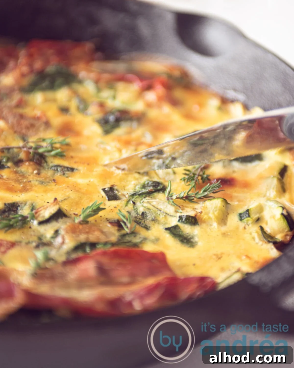 Fresh Zucchini and Spinach Frittata 3 A pan with a frittata with spinach and zucchini, topped with herbs and cheese