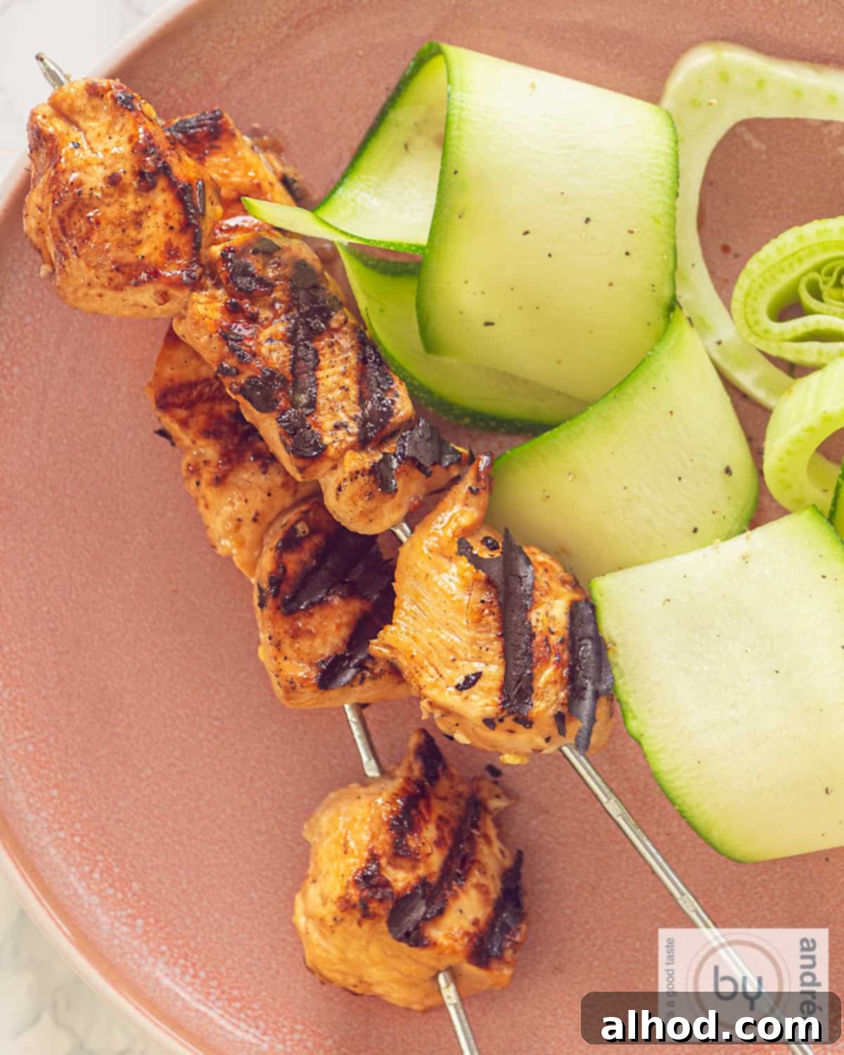 A plate with grilled chicken and cucumber.