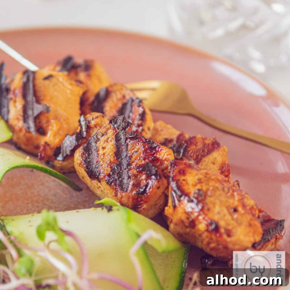 Soy-Mustard Glazed Chicken Skewers 5 A square photo of two skewers on a red plate with chicken marinated in mustard and ketjap and grilled.