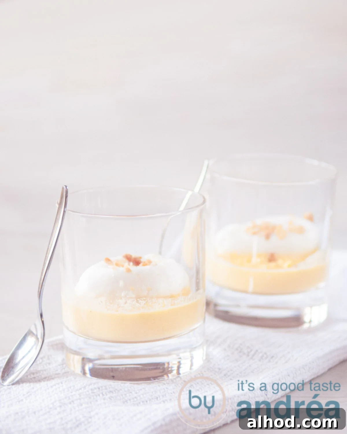 Floating Islands 2 Two glasses with Oeufs a la neige on a white cloth on a white background. Two spoons stand against the glasses