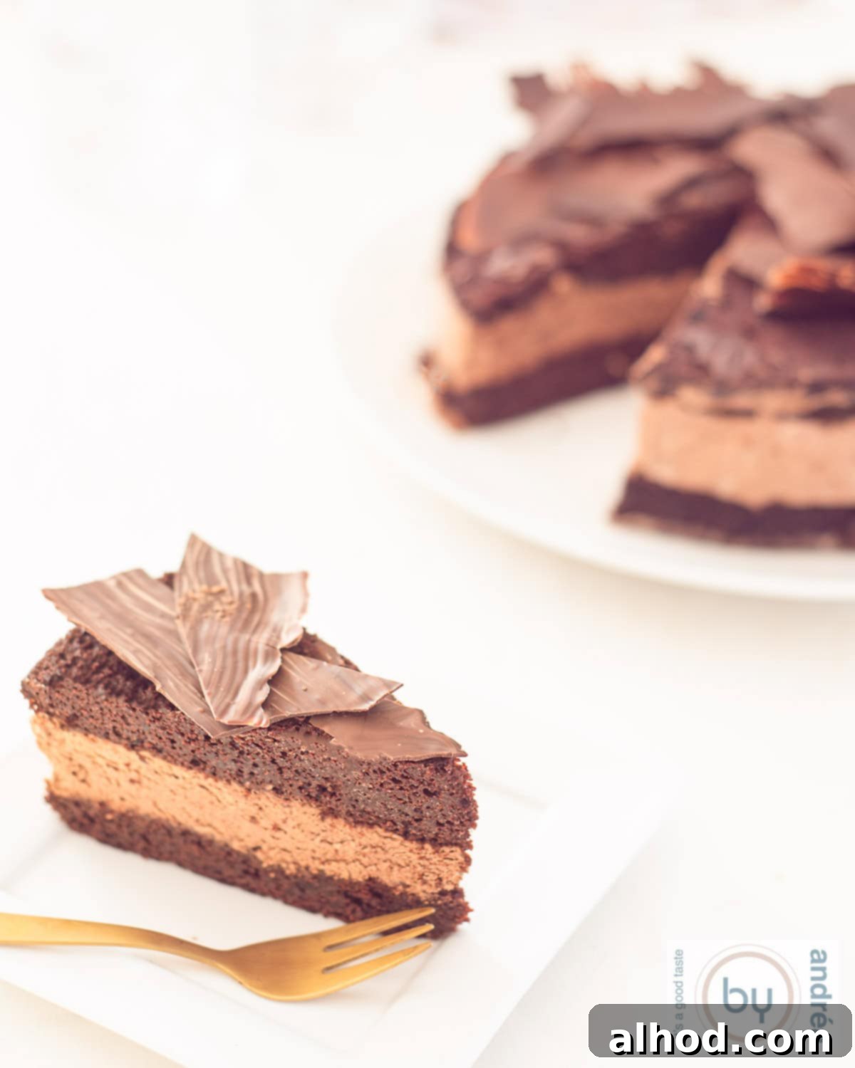 Dark Roast Chocolate Indulgence 3 Een hoogtefoto van een taartbord met een punt chocolademousse taart op een wit gebaksbord. De rest van de taart staat in de achtergrond,