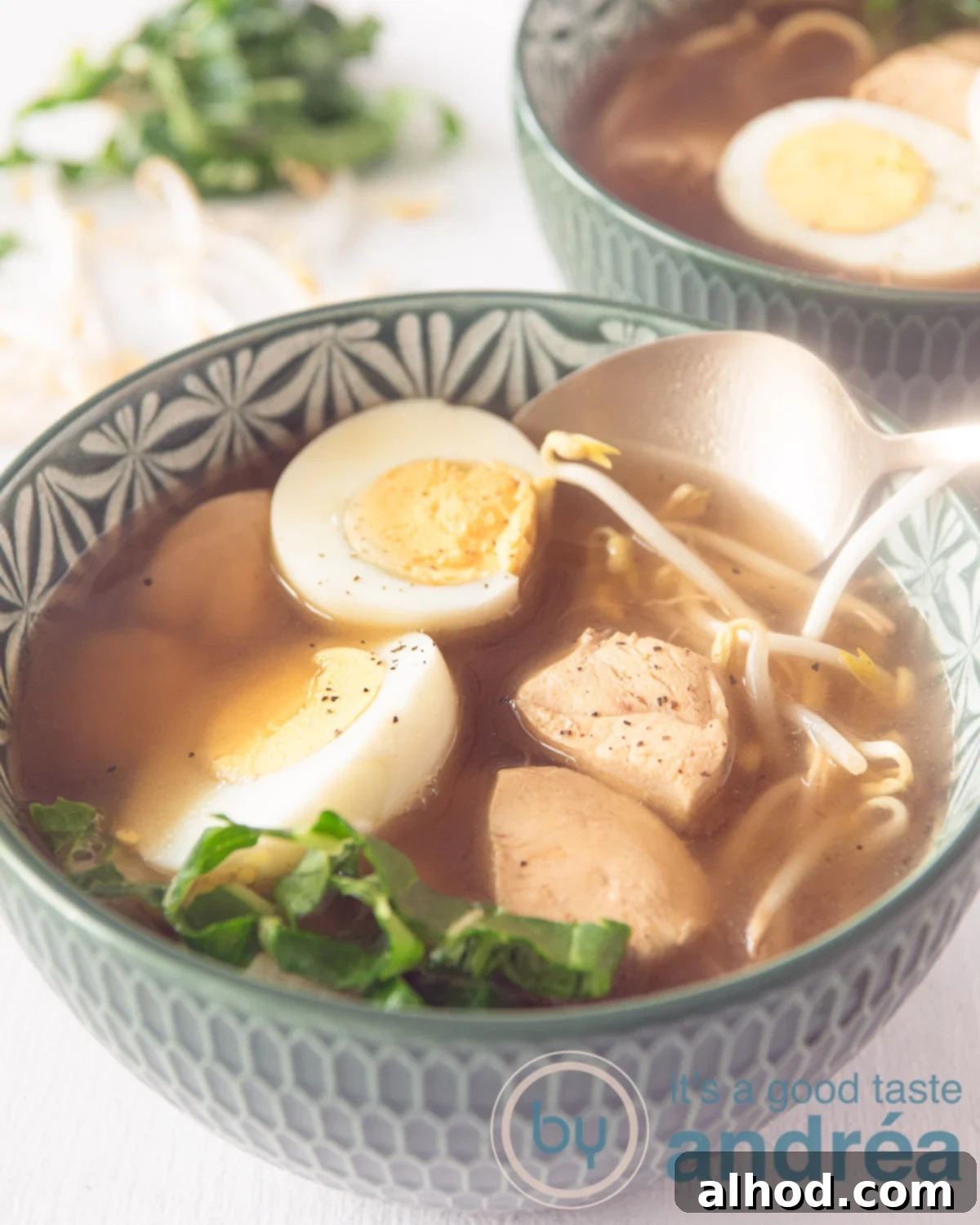 Making Japanese Chicken Ramen at Home 5 A vibrant green bowl brimming with rich ramen, tender chicken, crisp bean sprouts, perfectly cooked eggs, and fresh bok choy. A golden spoon elegantly scoops a bite, with a second bowl subtly positioned in the background.
