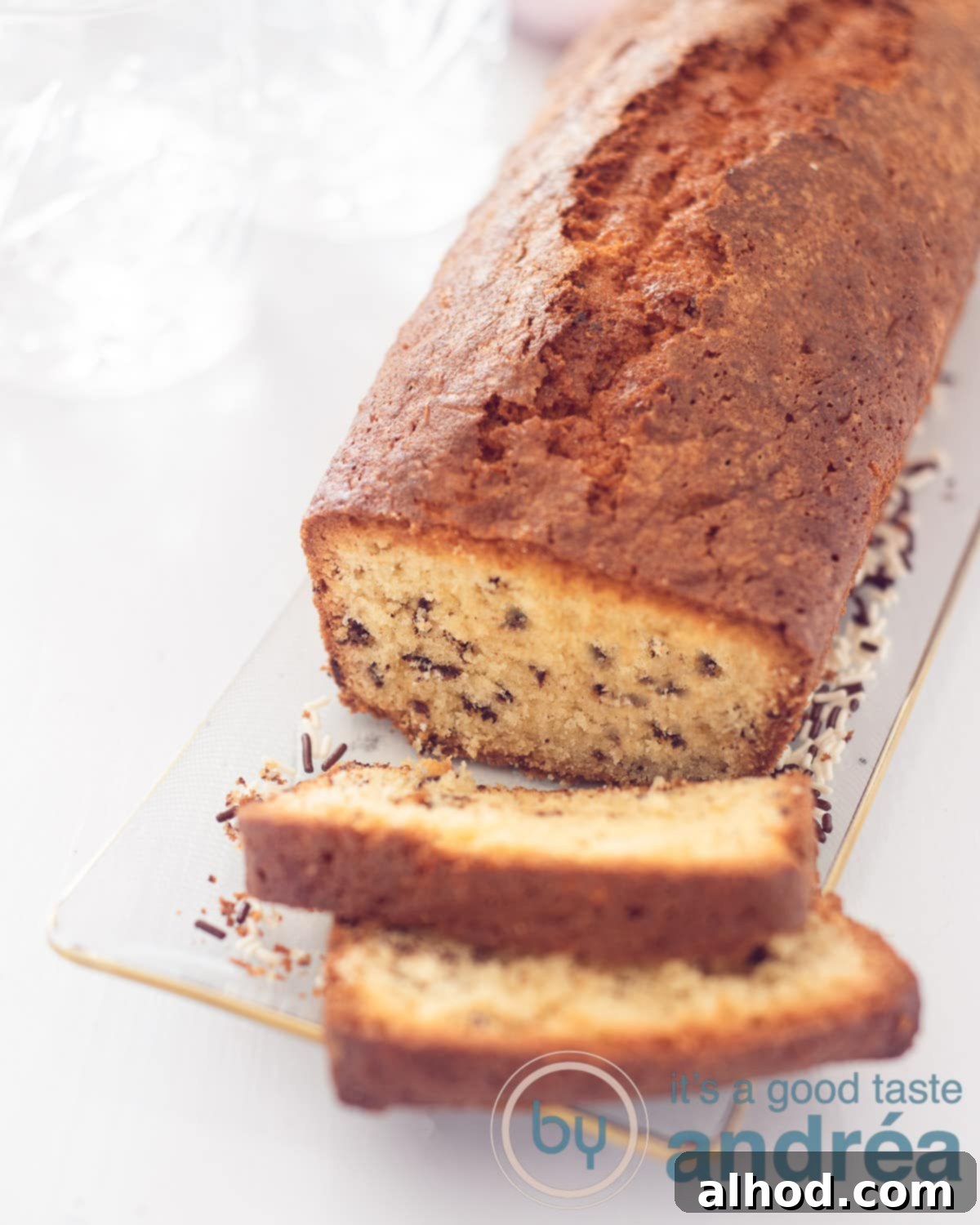 Dutch Hagelslag Vanilla Cake 2 An elevation photo with a sprinkles cake on a glass dish. Two slices cut off on a white background.