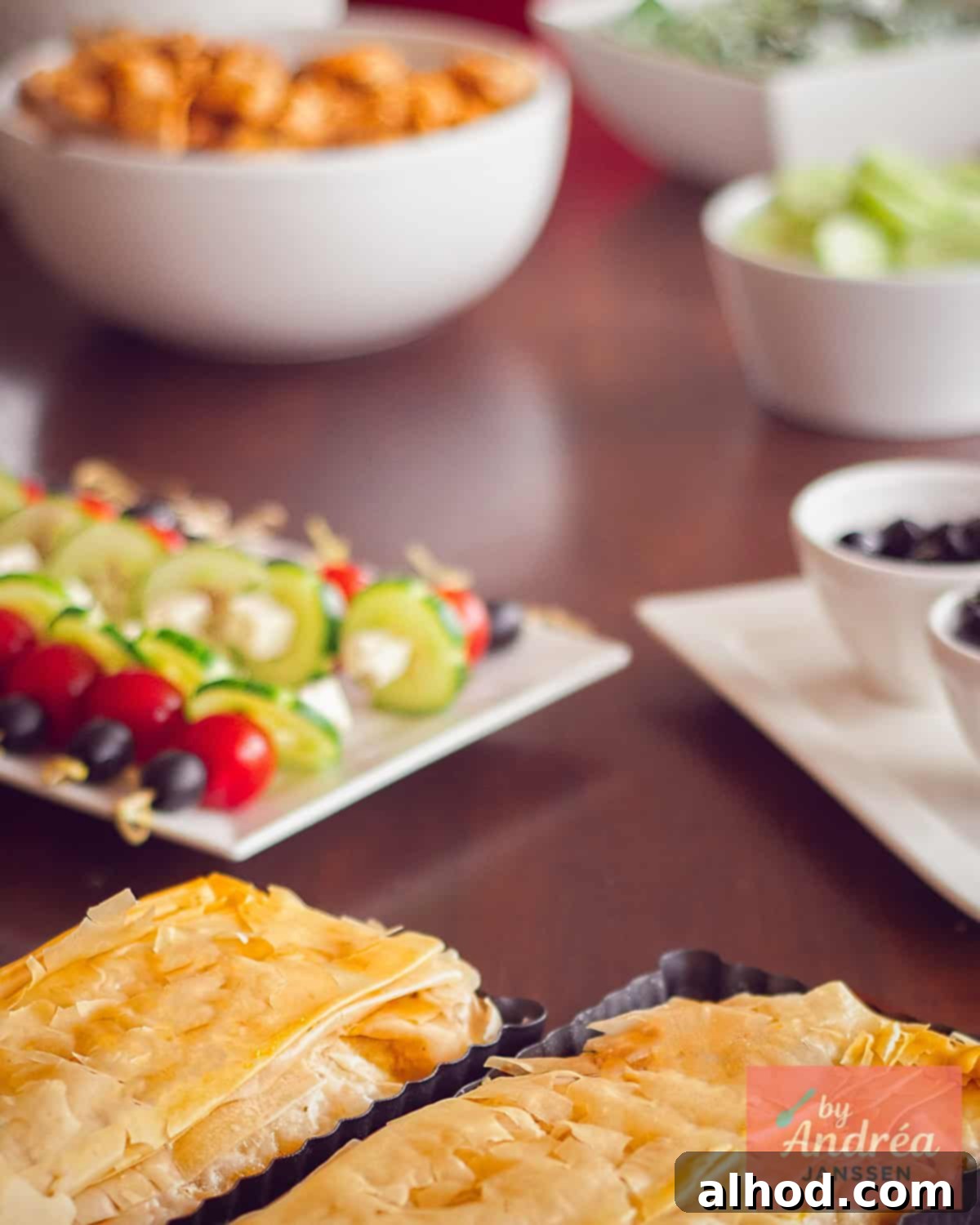 A brown buffet table with plates filled with salads and other Greek recipes