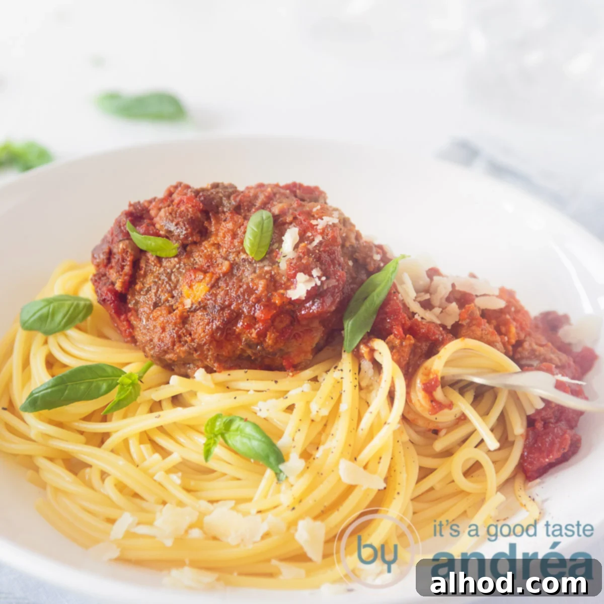 Sage Meatball Skillet Parm 6 A square photo with a white deep plate filled with spaghetti tomato sauce and tasty meatballs with sage and Parmesan cheese. A white background.