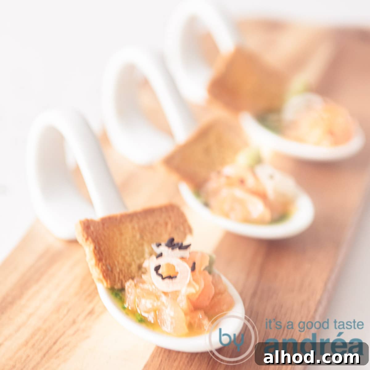 A wooden board with three white spoons filled with salmon, arugula oil and a piece of toast, angled