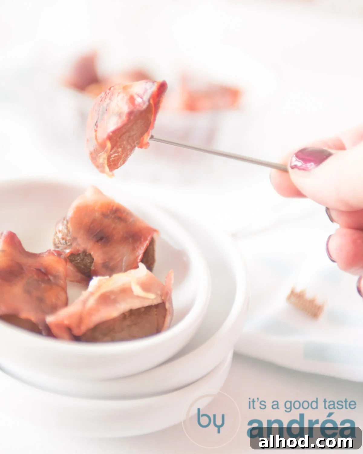 three white bowls stapled. Top one with a apricot bacon appetizer. A hand with a pricker with half a snack