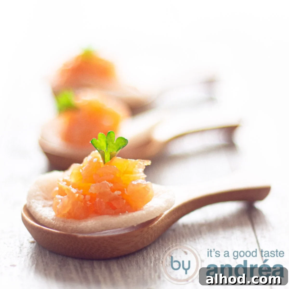 A square photo with three bamboo spoons in a row with prawn crackers, marinated smoked salmon and parsley on a white background
