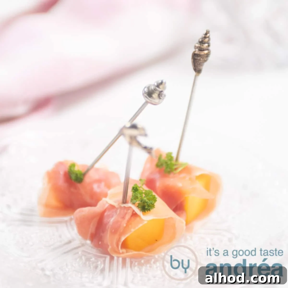 a square photo with a glass plate, with three prosciutto appetizers with mango