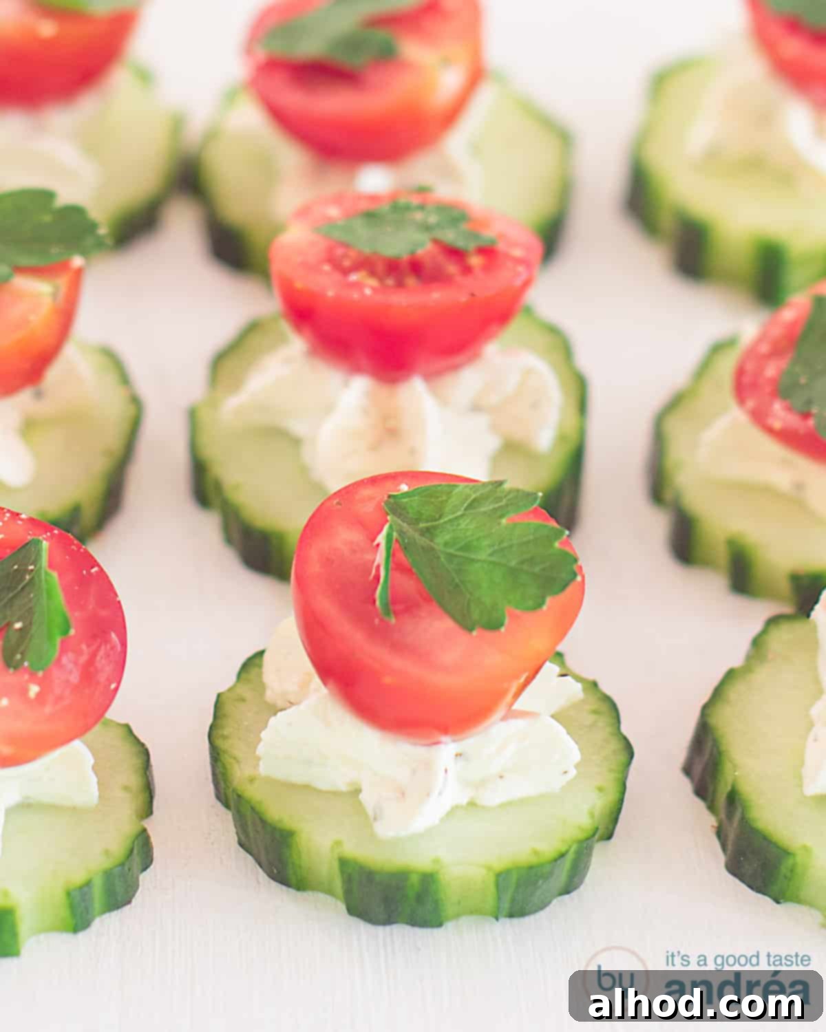 a plate with cucumber slices topped with herb cream cheese and a half cherry tomato