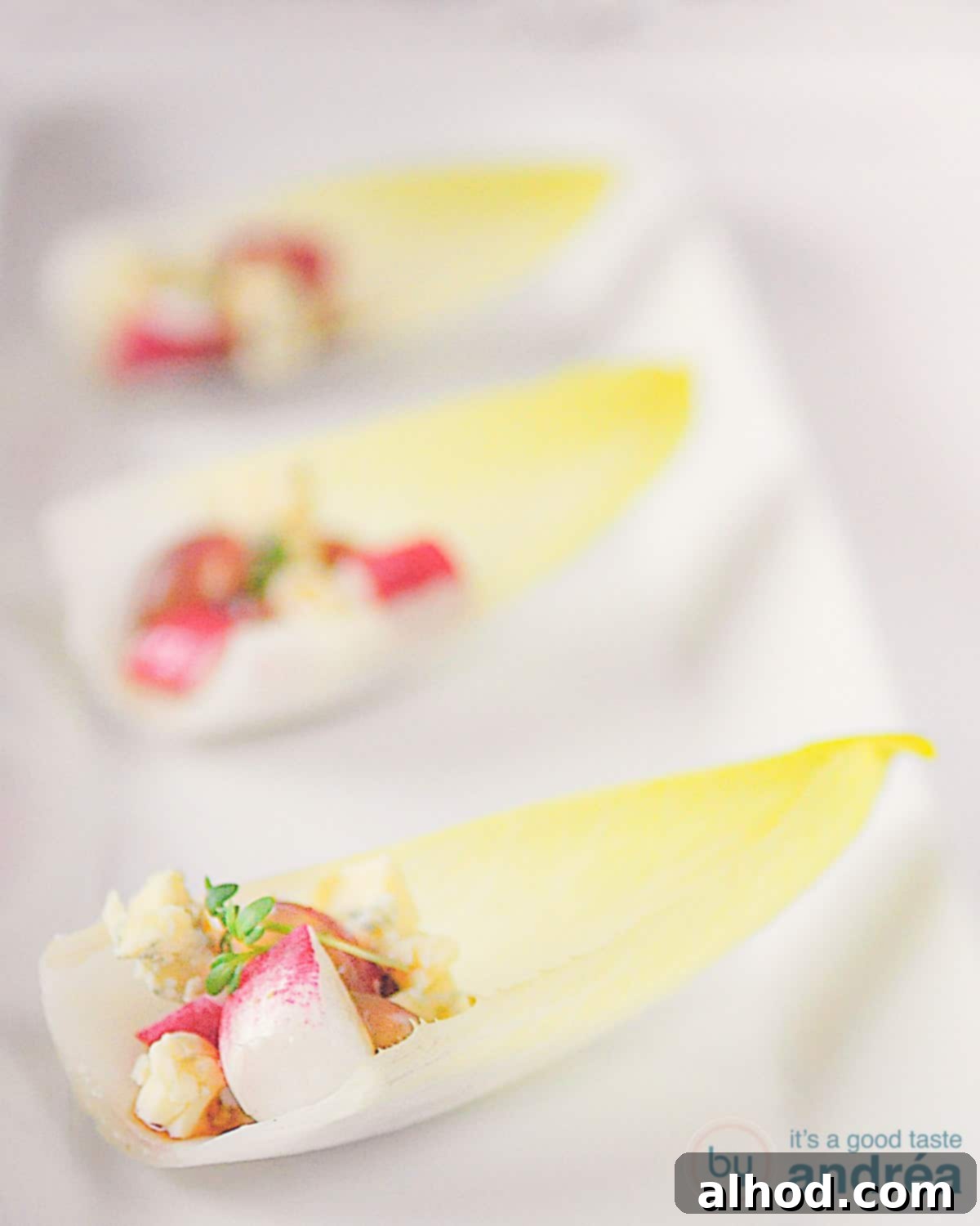 Witlof schuitjes op een schaal achter elkaar met een vulling van radijs, roquefort, pistache en druiven