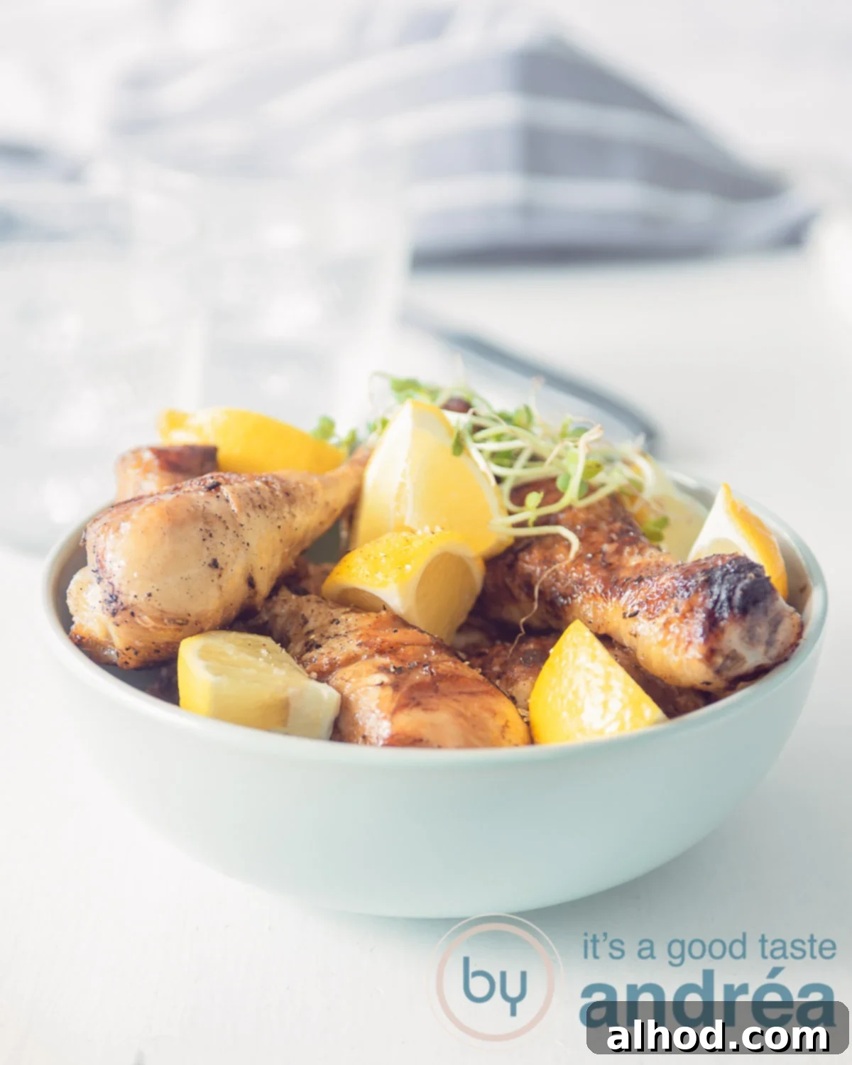 Braised Drumsticks in a Dutch Oven 5 Drumsticks with lemon and cres in a blue bowl on a white background. In the back a grey white cloth