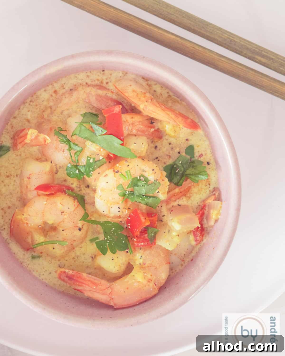 Simple Coconut Shrimp Curry with a Kick 2 A height photo showing a pink bowl of creamy shrimp in coconut milk curry.