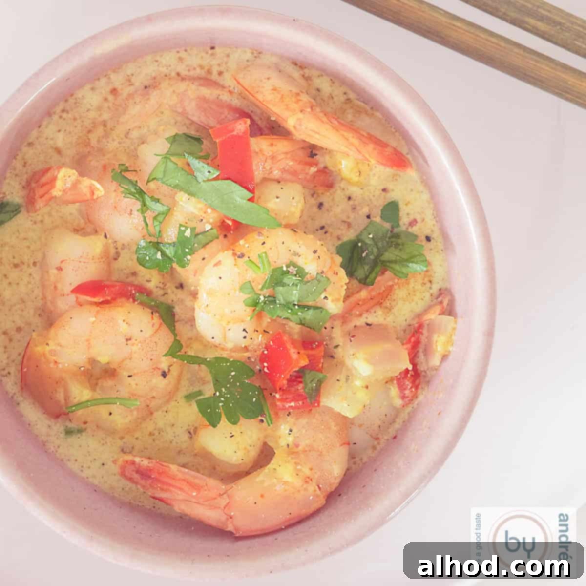 Simple Coconut Shrimp Curry with a Kick 4 A square photo of a pink bowl photographed from above filled with shrimp curry in coconut milk.