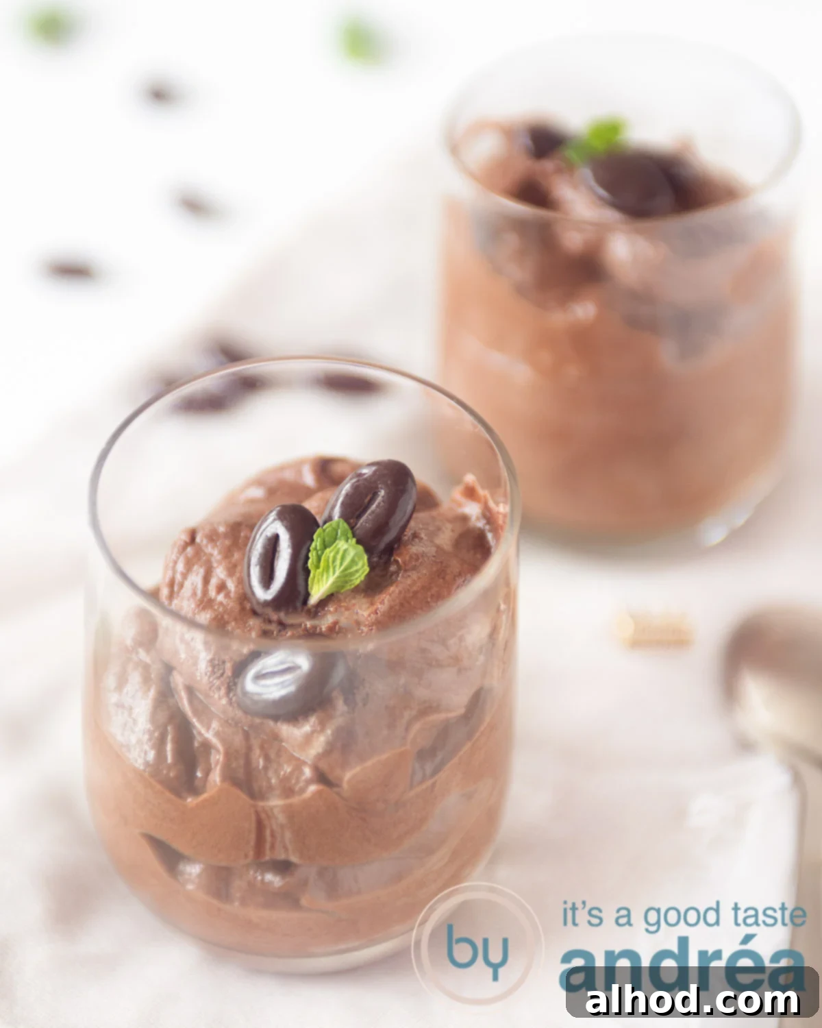 Velvety Egg-Free Dark Chocolate Mascarpone Mousse 6 Two glasses filled with a mousse of dark chocolate. Garnished with chocolate beans and mint leaves. Some chocolate scattered around