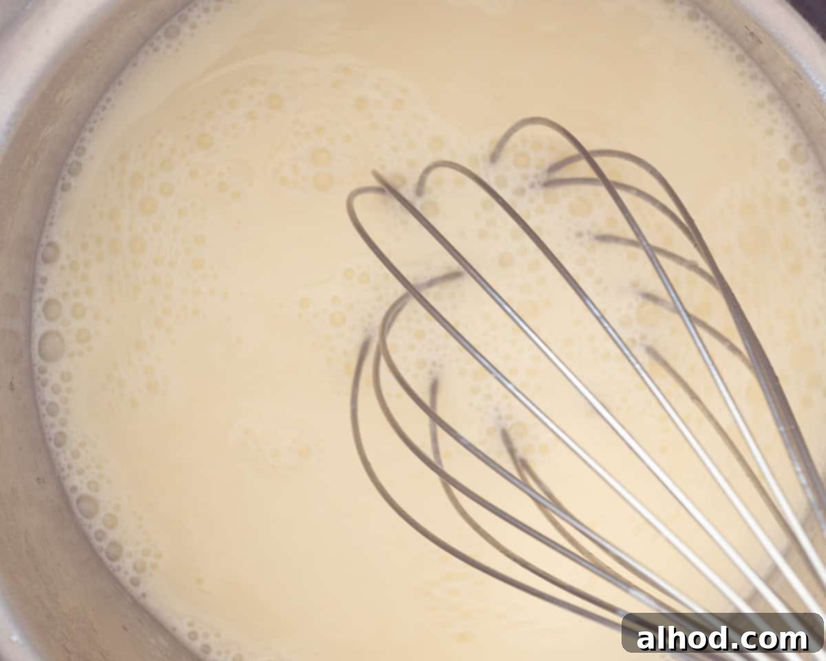 Easy 3-Ingredient Creamy Lemon Custard 6 A saucepan with lemon custard with a whisk