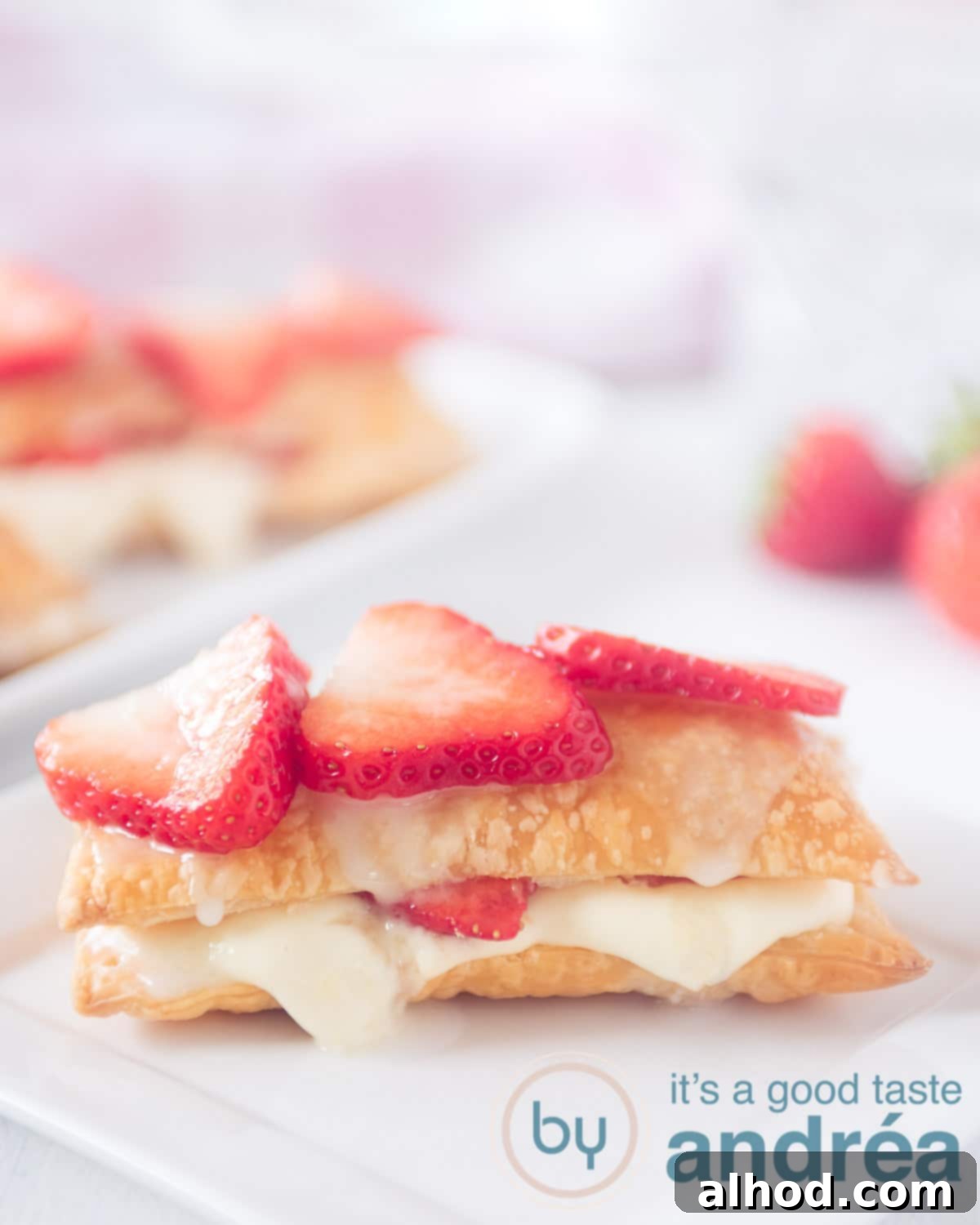 Decadent Strawberry Napoleon 2 A beautifully presented strawberry Napoleon on a white plate, with more pastries in the background, all against a clean white setting.