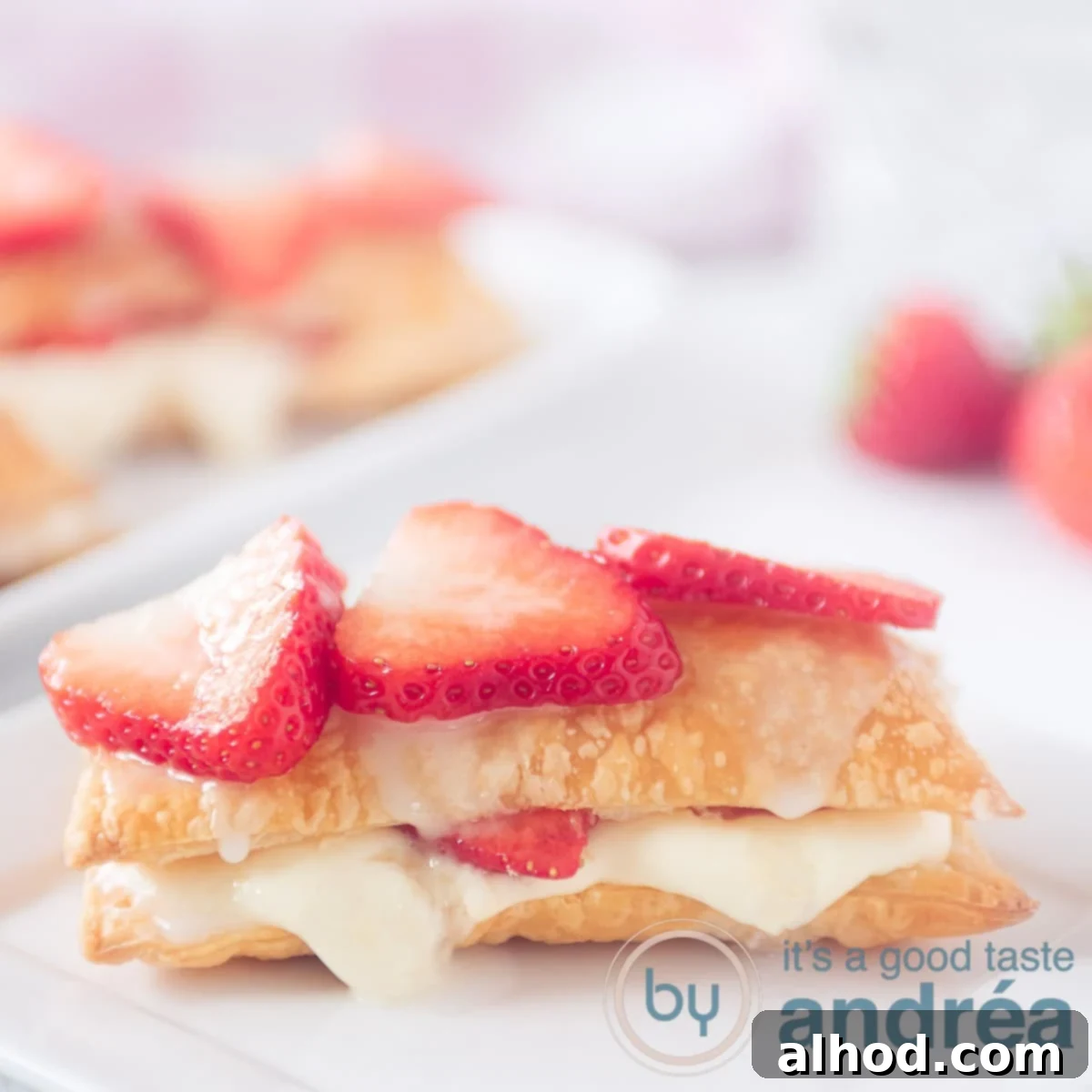 Decadent Strawberry Napoleon 6 A square photo with a strawberry tompouce with strawberries on top. More tompouces in the background.