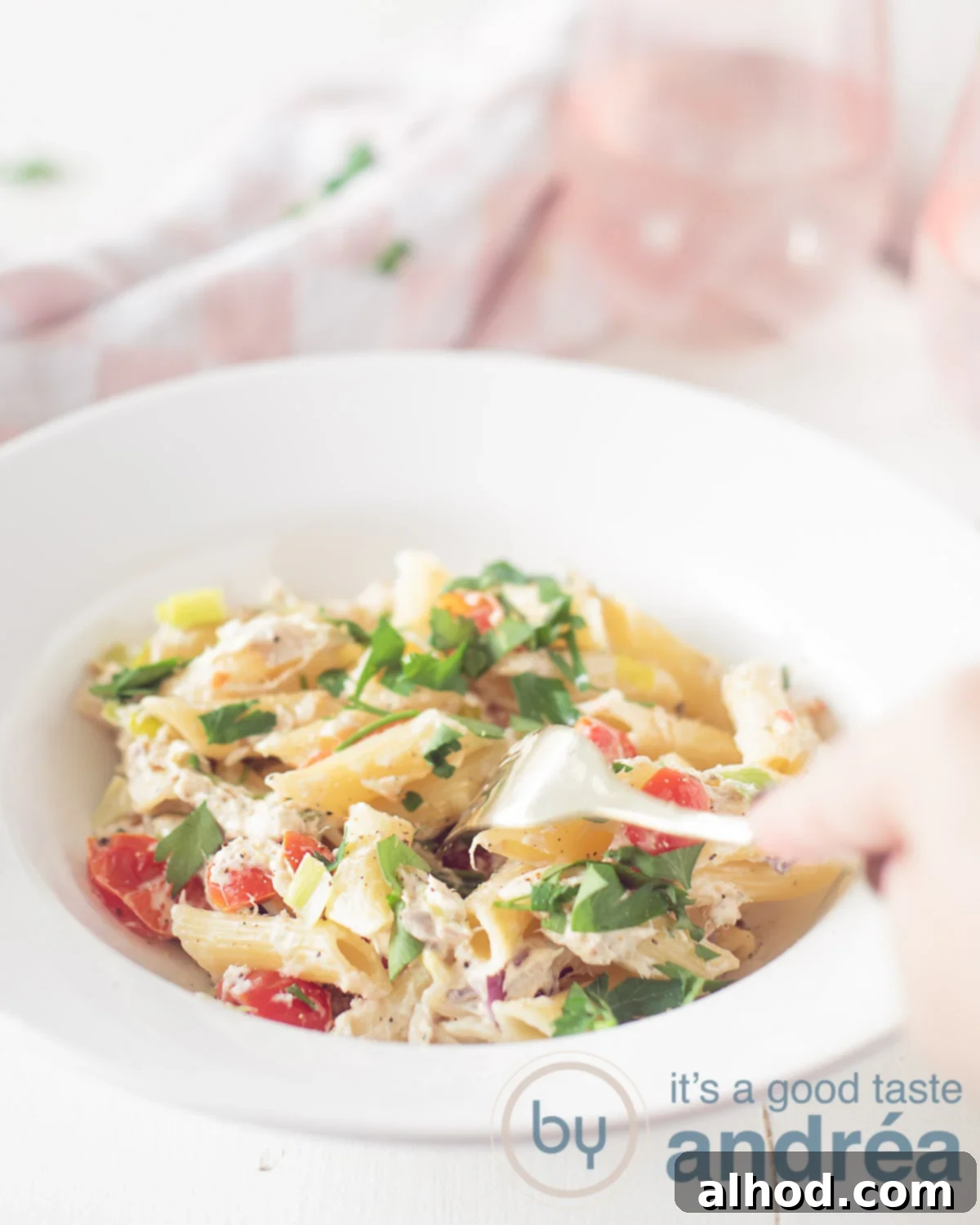 Velvety Smoked Mackerel Pasta 5 A white plate with smoked mackerel pasta in a creamy sauce on a white background. A white pink towel in the back. A fork pricks in the pasta.