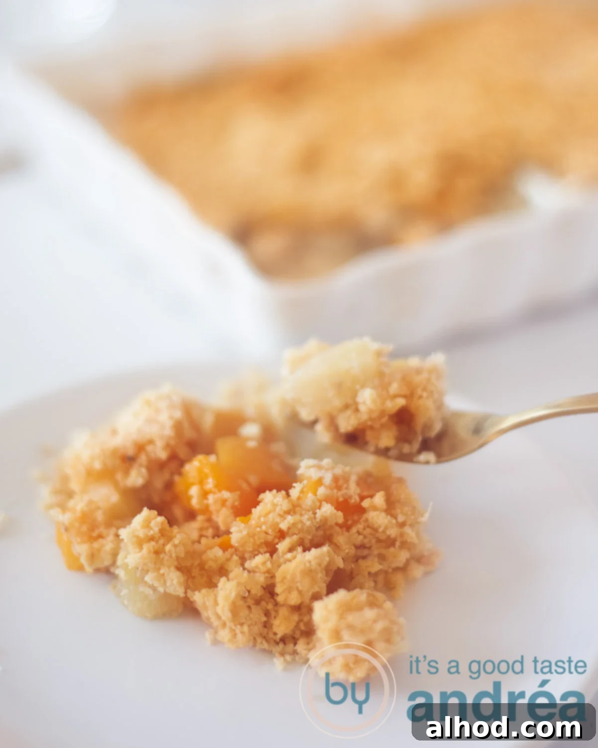 Golden Apple Peach Crumble 5 A slice of warm Apple Peach Crumble on a white plate, ready to be enjoyed, with the full baking dish subtly blurred in the background.