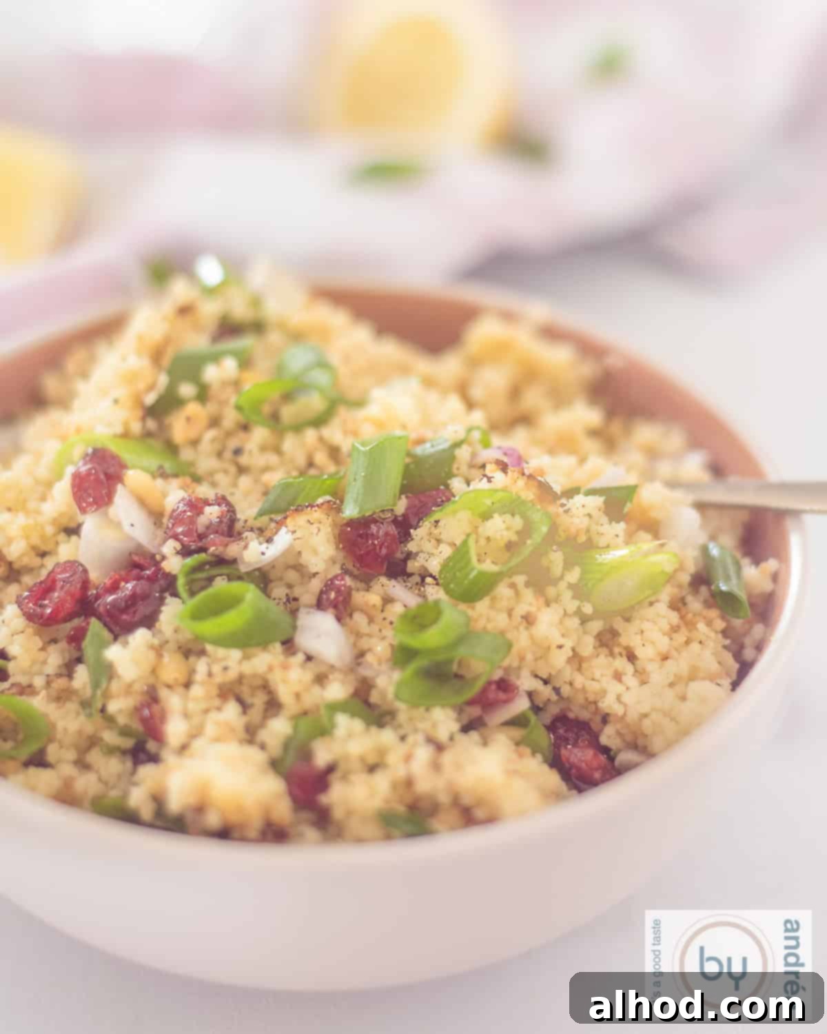 Zesty Cranberry Couscous Salad 2 A pink bowl with couscous, cranberries, lemon, pine nuts