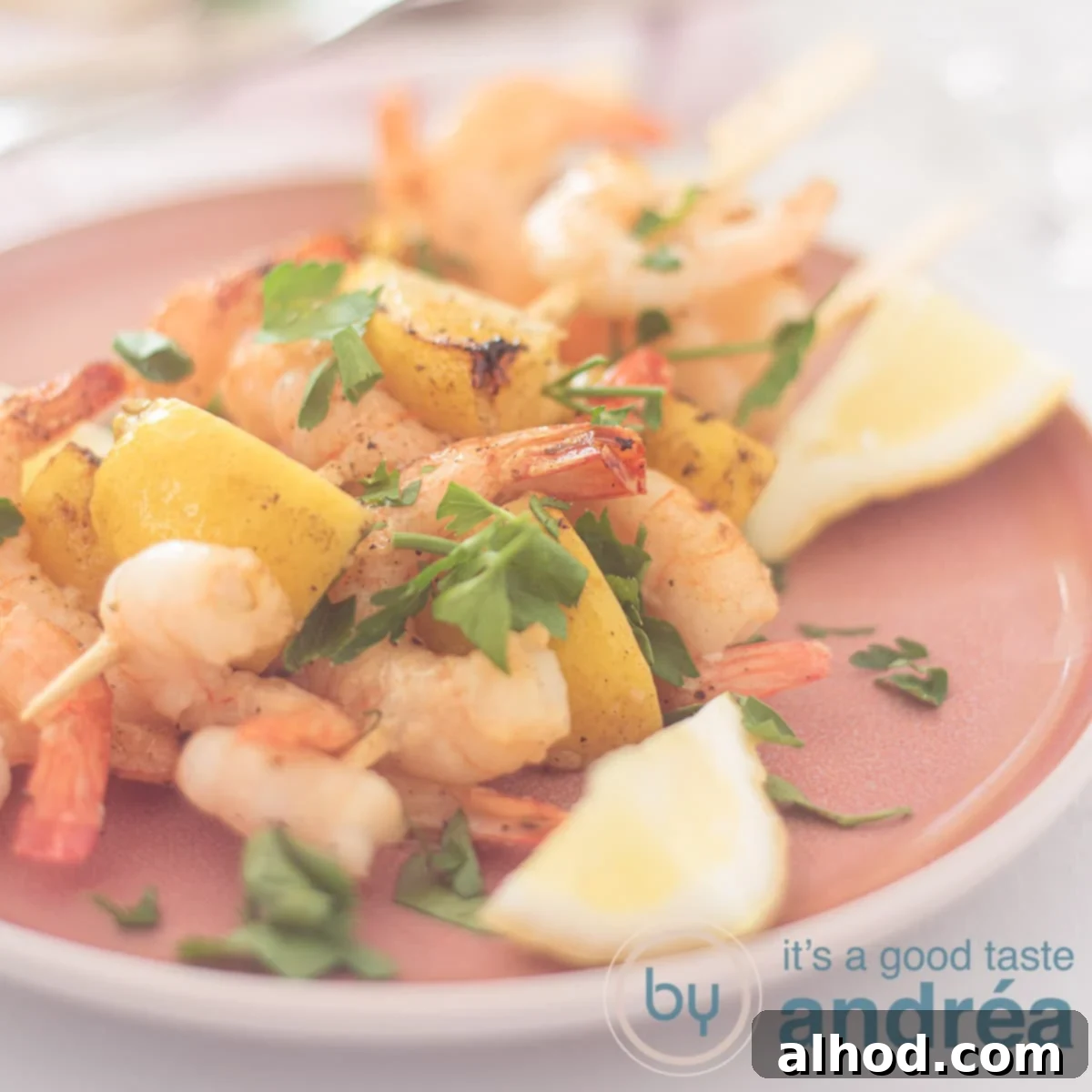 Grilled Lemon-Garlic Shrimp Skewers 6 A square photo with a pink plate with three shrimp skewers interspersed with lemon and garnished with parsley.