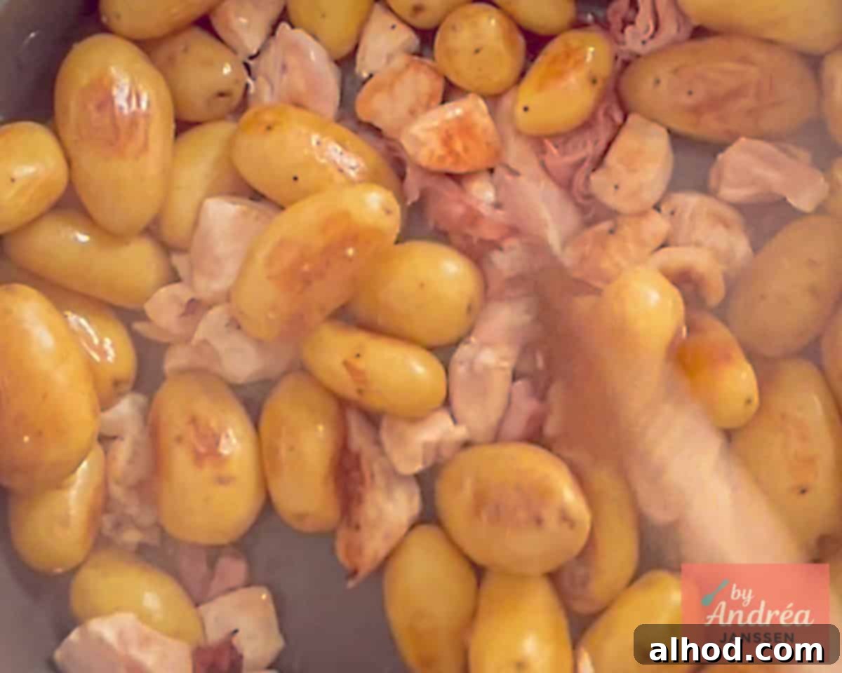 Golden Skillet Chicken with Crispy Bacon and Potatoes 4 A mix of golden-brown baby potatoes, crispy bacon, tender chicken pieces, aromatic shallots, garlic, and fresh thyme cooking together in a large skillet, developing rich flavors.