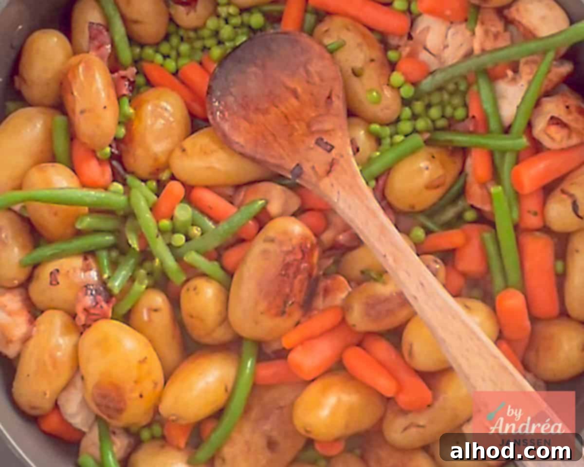 Golden Skillet Chicken with Crispy Bacon and Potatoes 5 Colorful frozen vegetables, including carrots, green beans, and peas, being stirred into the skillet with chicken, potatoes, and bacon, adding freshness and nutrients.