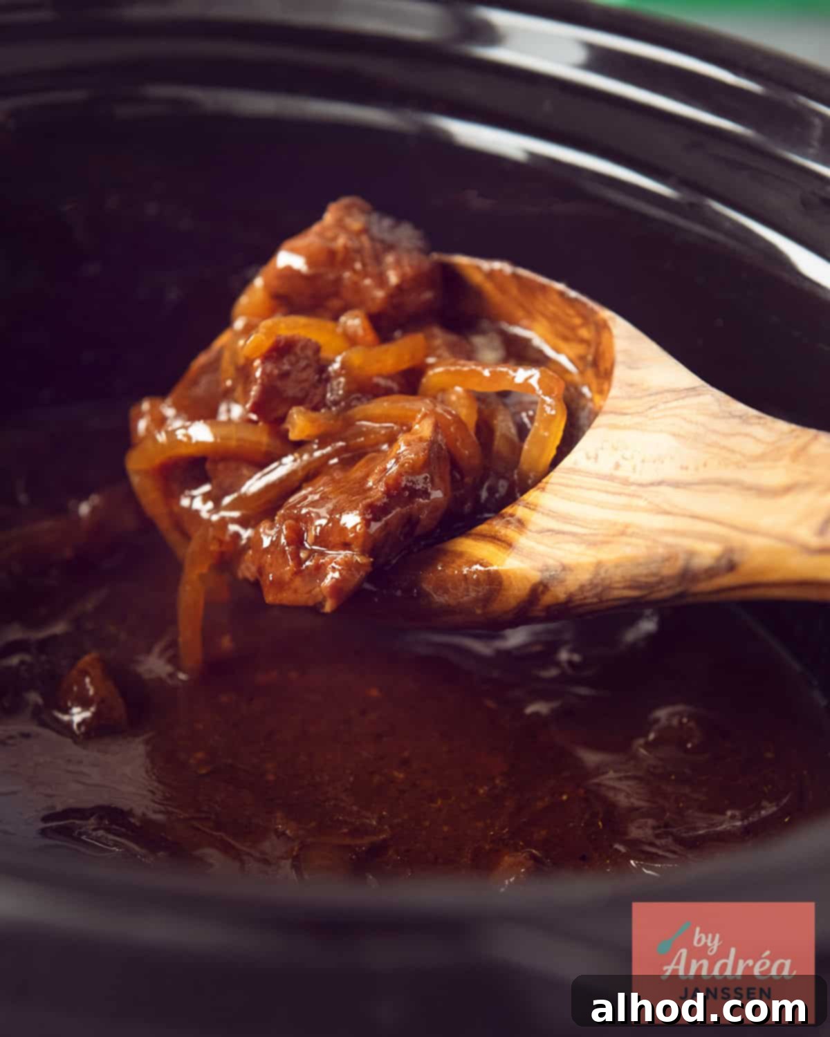 Dutch Stoofvlees Fries 8 A slow cooker where a wooden spoon scoops stew meat