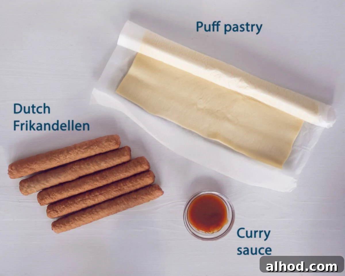 A flat lay of the essential ingredients for Dutch Frikandelbroodje: a sheet of puff pastry, frikandel sausages, a bowl of curry sauce, and a small bowl with a beaten egg.