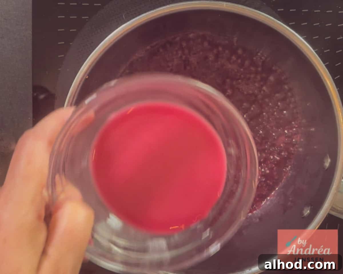 The cherry juice is being thickened in a saucepan with a potato starch slurry, creating a glossy texture.