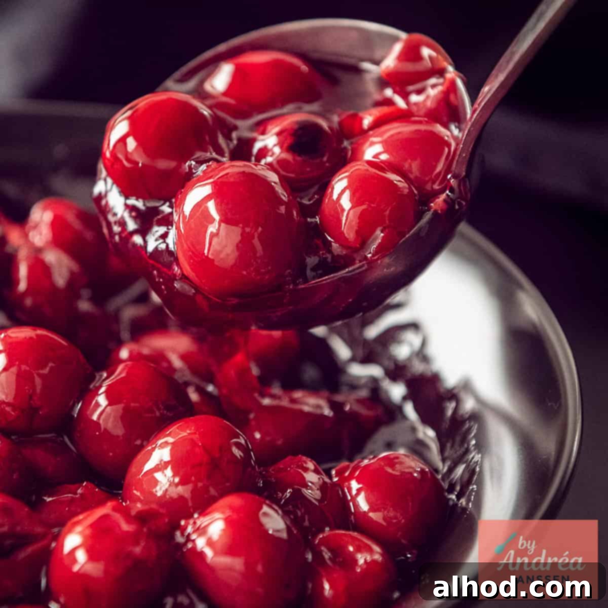 A square photo of a bowl of cherry pie filling being scooped out.