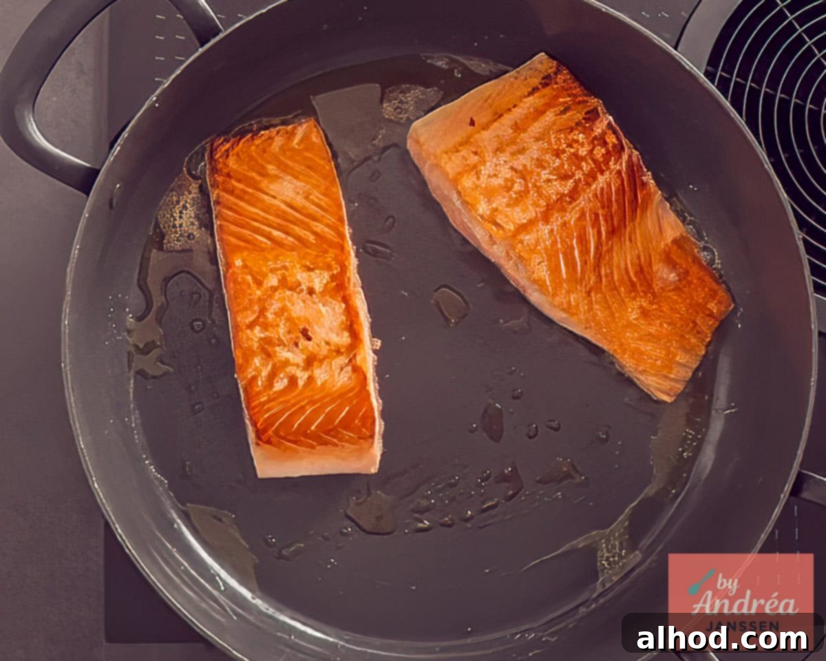 Two salmon fillets fried in a frying pan
