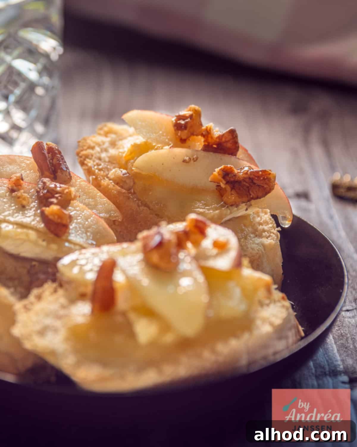 Three bruschetta in a black bowl with apple, Brie, walnut and honey.