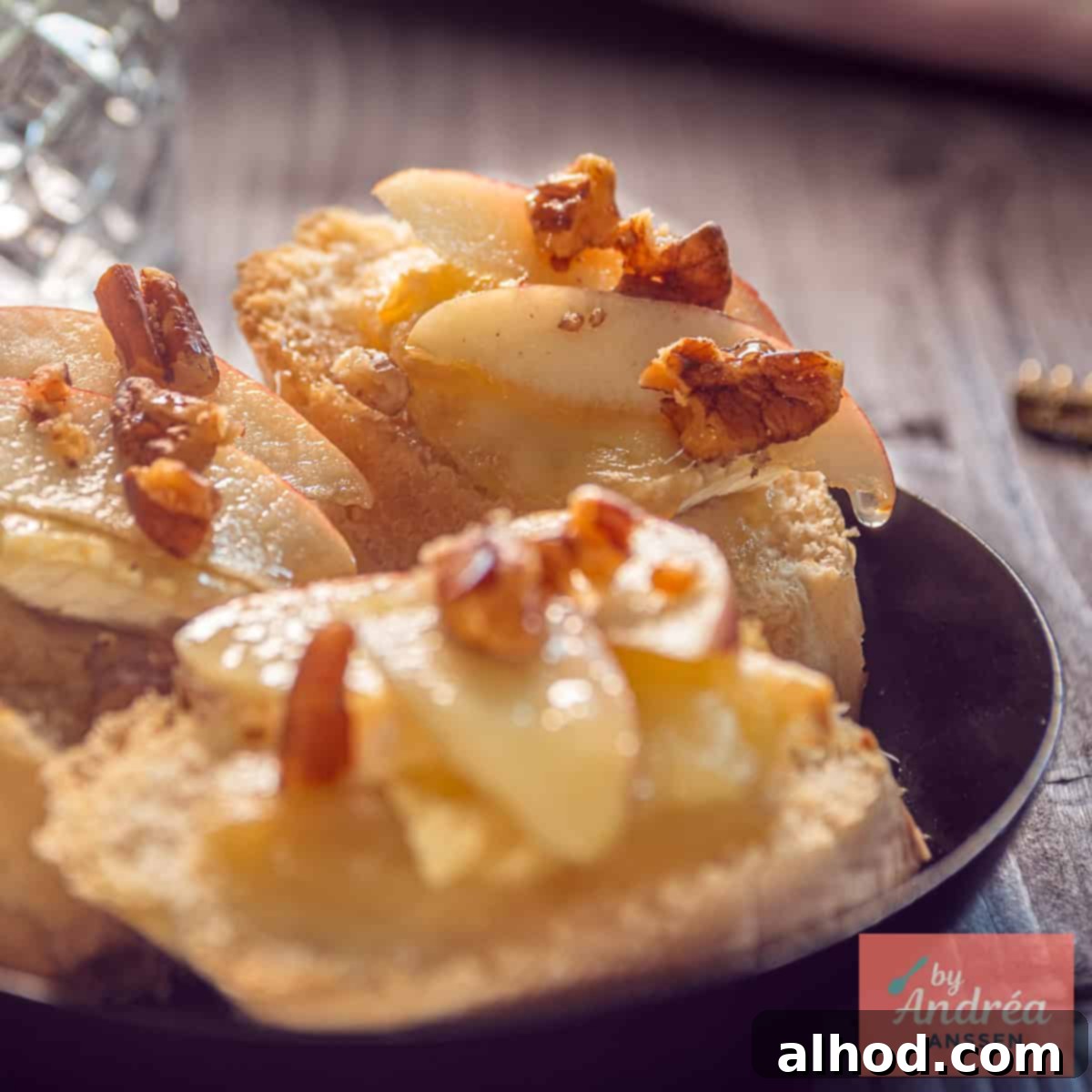 A black bowl with three slices of baguette with honey, apple, Brie and walnut