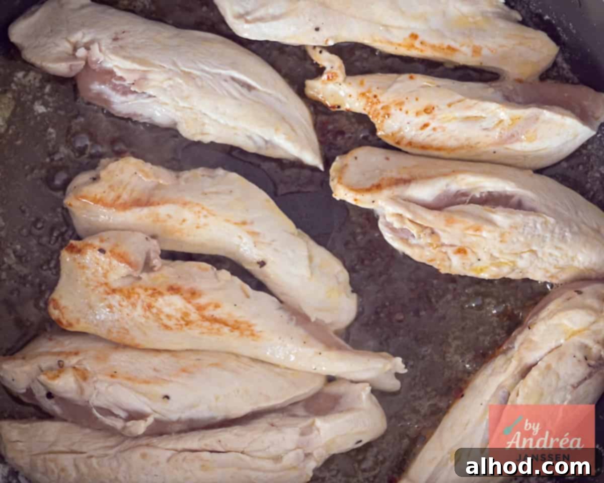Close-up of chicken being pan-fried to a golden brown in a skillet.