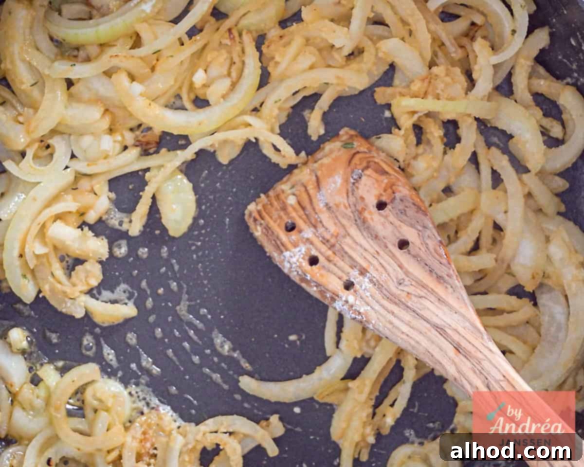 Onions being sautéed in a pan with flour and herbs, creating a flavorful base for the sauce.