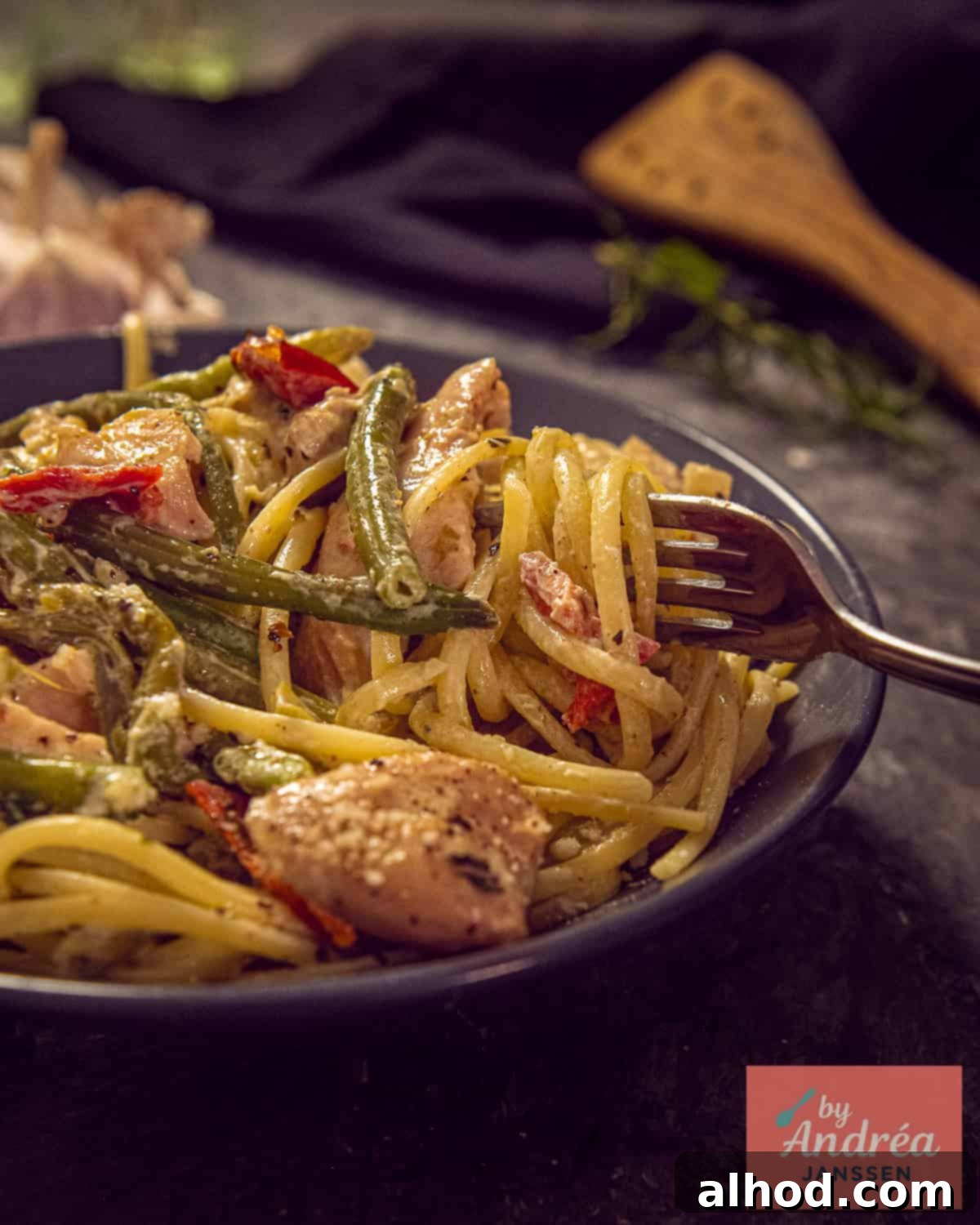 Slow Cooker Creamy Tuscan Pesto Chicken 8 A gray plate with pasta and Slow Cooker Tuscan chicken with green beans, showcasing a delicious and satisfying meal.