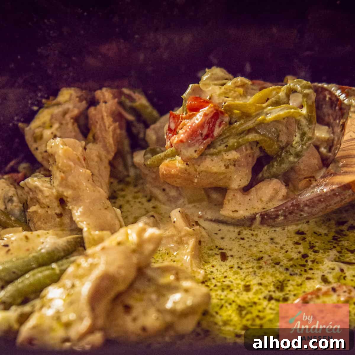 A square photo of a slow cooker with Tuscan chicken being scooped out of it.