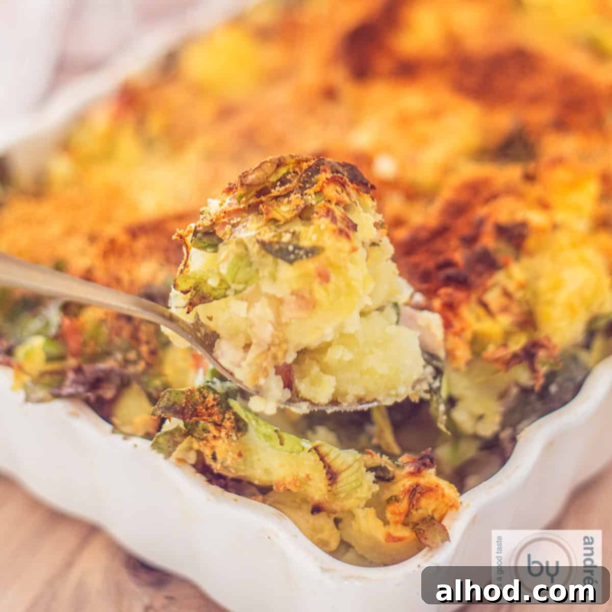 Dutch Baked Andijvie Stamppot (Endive Mash) served in a white dish, showcasing its golden top.